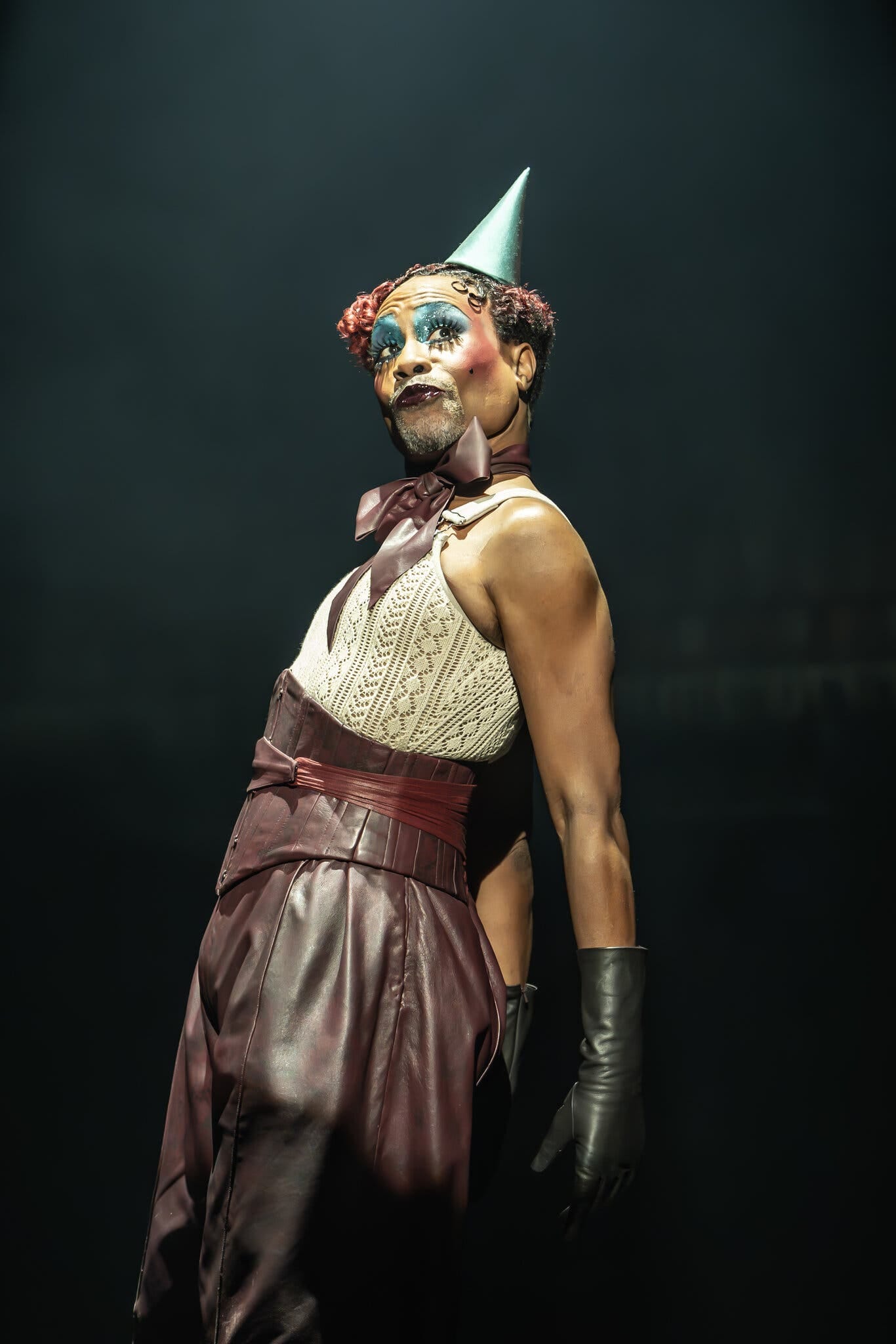 DIY Emcee Costume Guide: Cabaret Broadway 2024 Revival A heavily made up Billy Porter performs in a green birthday party hat, cream-colored tank top and burgundy leather pants.